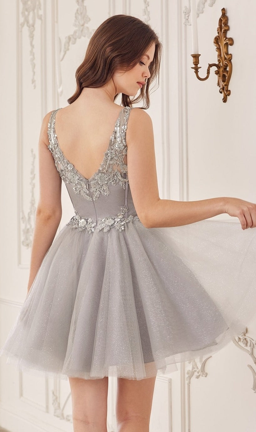 A woman in the Sequin-Corset Short A-Line Homecoming Dress CY019, featuring silver-gray sequin lace and sleeveless design, stands indoors holding her skirt and facing away from the camera.
